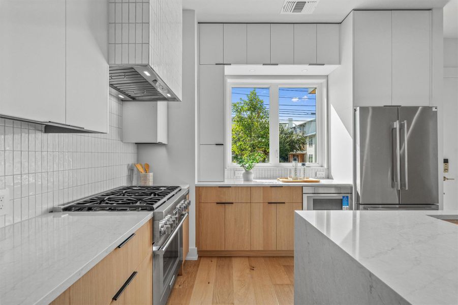 The stunning kitchen features sleek quartz countertops, modern flat front cabinetry, a built-in pantry, and a center island with a stunning waterfall edge. The stunning kitchen features sleek quartz countertops, modern flat front cabinetry, a built-in pantry, and a center island with a stunning waterfall edge.