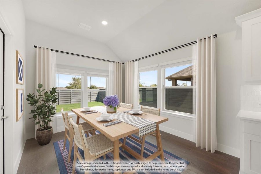 Bright dining area with vaulted ceiling, wood table, four chairs, and large windows overlooking backyard Bright dining area with vaulted ceiling, wood table, four chairs, and large windows overlooking backyard