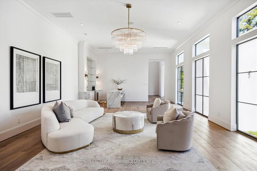 This expansive great room unites a sleek luxury bar, inviting living room, and elegant formal dining area for seamless entertaining. Durango Doors lead to a spacious covered patio, creating a perfect indoor- outdoor flow. White oak flooring and exquisite designer lighting enhance the room's sophisticated ambiance.