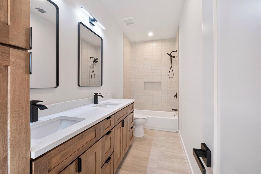 Bathroom featuring double vanity, shower / bath combination, and recessed lighting