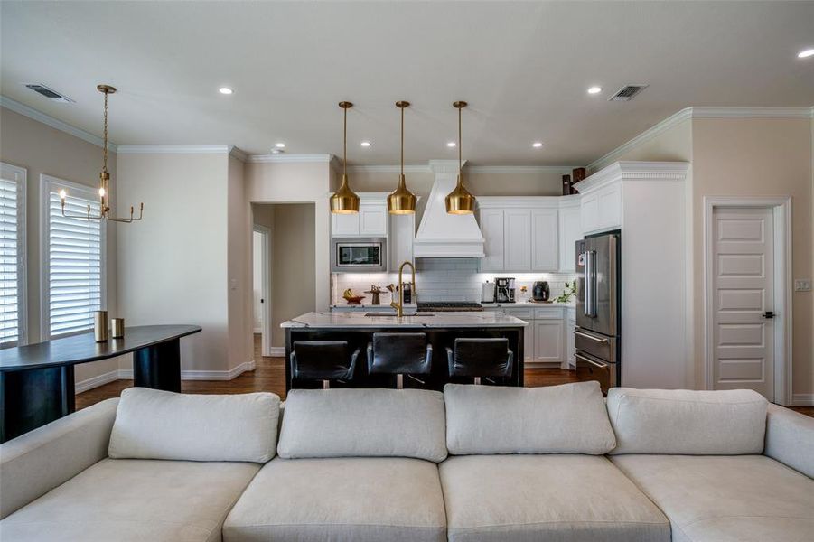 Living room featuring hardwood / wood-style floors, crown molding, sink, and a chandelier