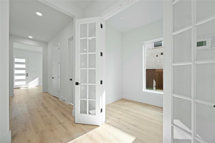 Corridor featuring light wood-type flooring, plenty of natural light, and recessed lighting