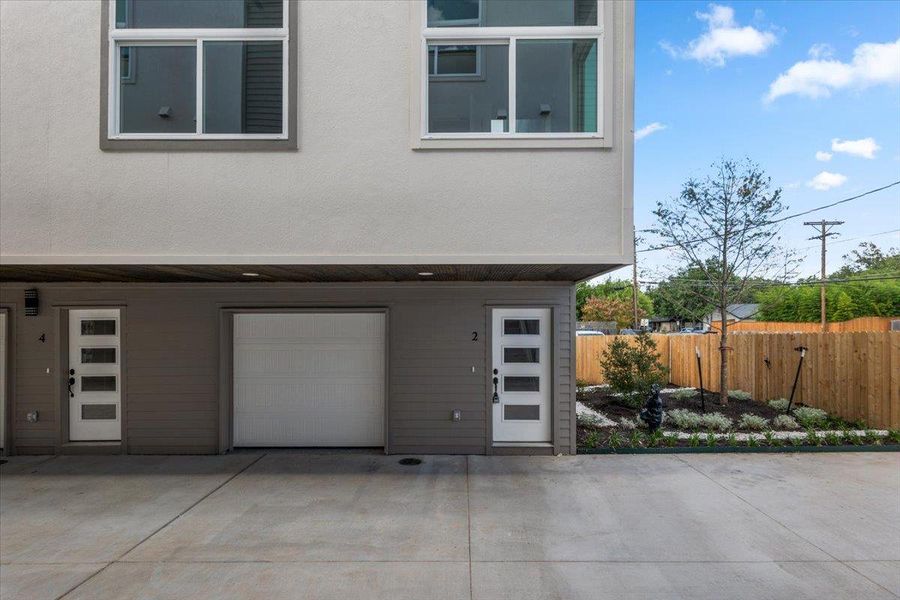 Modern townhome exterior with attached garage and meticulously landscaped private yard.