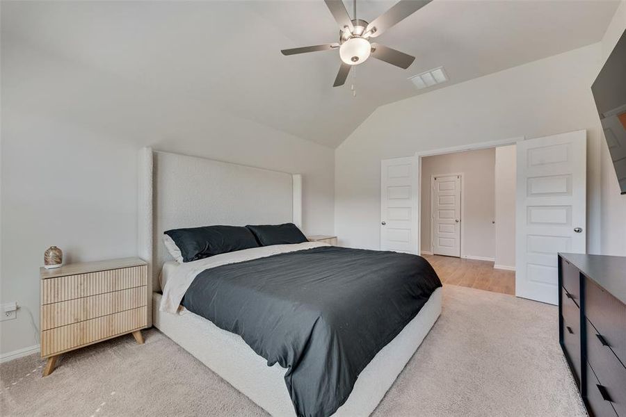 Bedroom featuring a ceiling fan, vaulted ceiling, and light carpet Bedroom featuring a ceiling fan, vaulted ceiling, and light carpet