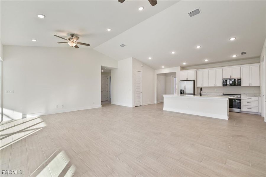 Unfurnished living room with recessed lighting, wood finish floors, lofted ceiling, and a ceiling fan