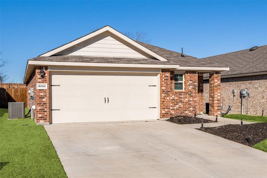 Ranch-style home with an attached garage, driveway, central AC, and brick siding