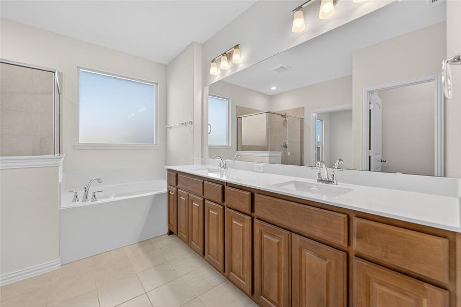 Full bathroom with double vanity, a bath, light tile patterned floors, and tiled shower