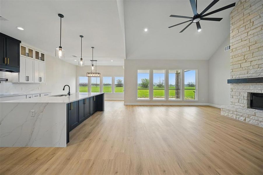Unfurnished living room featuring high vaulted ceiling, light wood finished floors, a stone fireplace, and recessed lighting Unfurnished living room featuring high vaulted ceiling, light wood finished floors, a stone fireplace, and recessed lighting