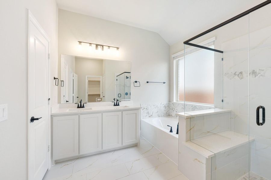 Master bathroom with double vanity, soaking tub, glass shower, and white marble tile throughout