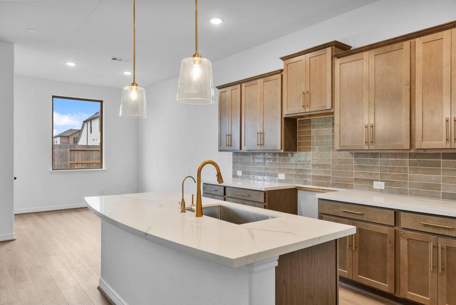 Kitchen with abundant cabinetry, generous countertop space, a walk-in pantry, and a center island designed for breakfast bar seating and everyday gathering.