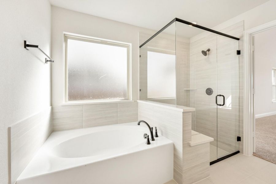 Bathroom with soaking tub, glass-enclosed walk-in shower, tile walls, and black hardware accents