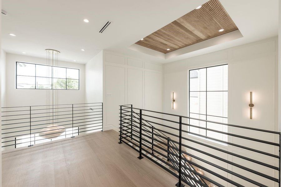 An airy second-story walkway designed to celebrate the home’s vertical scale, offering uninterrupted sightlines across the open-concept layout. Sunlight pours through clerestory-style windows, enhancing the clean architectural lines and understated luxury throughout.
