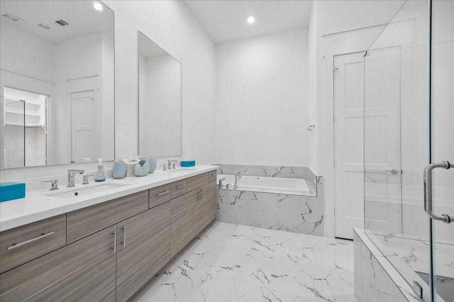 Luxurious primary bath with a separate soaking tub, large walk-in shower, and quartz countertops. Luxurious primary bath with a separate soaking tub, large walk-in shower, and quartz countertops.