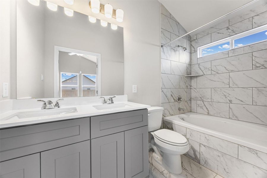 Elegant tile surrounds the soaking tub in a modern bathroom complete with dual sinks. Elegant tile surrounds the soaking tub in a modern bathroom complete with dual sinks.