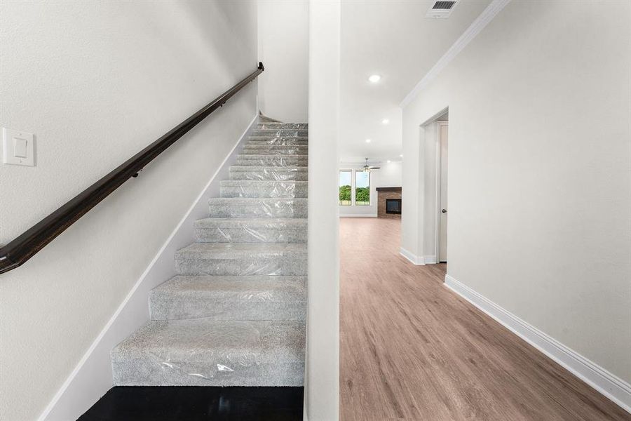 Stairway with a fireplace, wood finished floors, ornamental molding, recessed lighting, and ceiling fan Stairway with a fireplace, wood finished floors, ornamental molding, recessed lighting, and ceiling fan