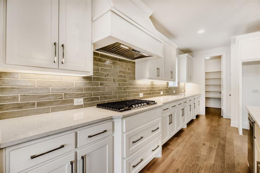 Kitchen featuring white cabinets, light wood-style floors, light stone counters, recessed lighting, and stainless steel appliances