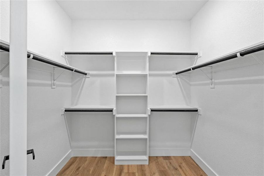 Walk in closet with hardwood / wood-style flooring