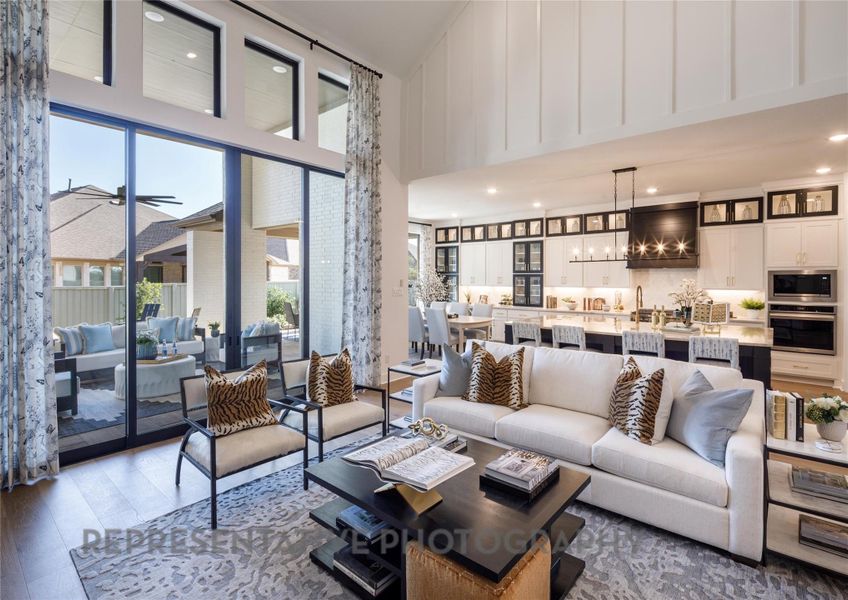 Living area featuring a high ceiling, ceiling fan, wood finished floors, a chandelier, and recessed lighting