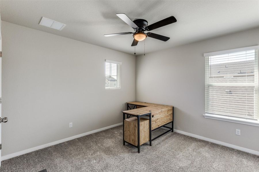 Office with light carpet and a ceiling fan