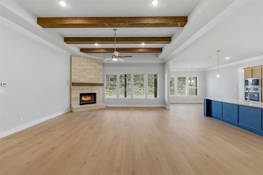 Unfurnished living room with recessed lighting, a stone fireplace, light wood-style flooring, ceiling fan, and crown molding