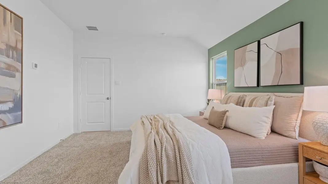 Primary bedroom with ceiling fan, plush carpeting, and a large walk-in closet.