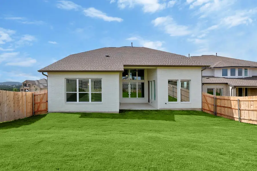 Rear view of property featuring a fenced backyard, brick siding, roof with shingles, and a patio area
