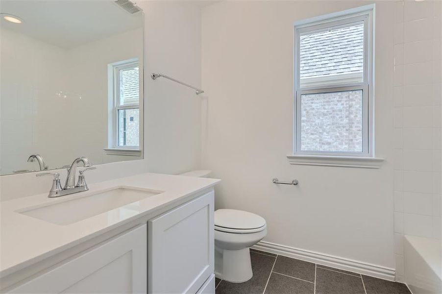 Full bathroom featuring tile floors, plenty of natural light, vanity, and toilet