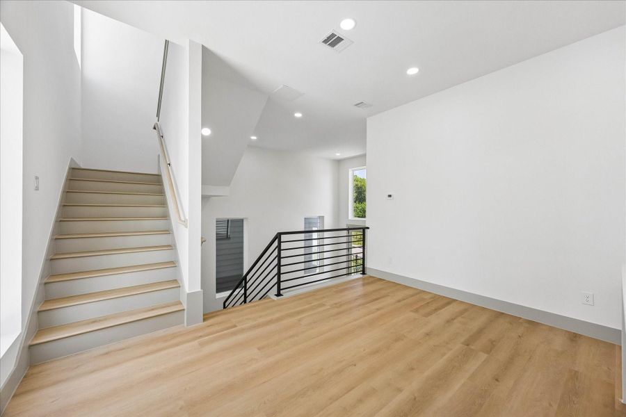 A dramatic open stairwell with custom wood slat detailing creates an architectural focal point while connecting each level with warmth and natural light.