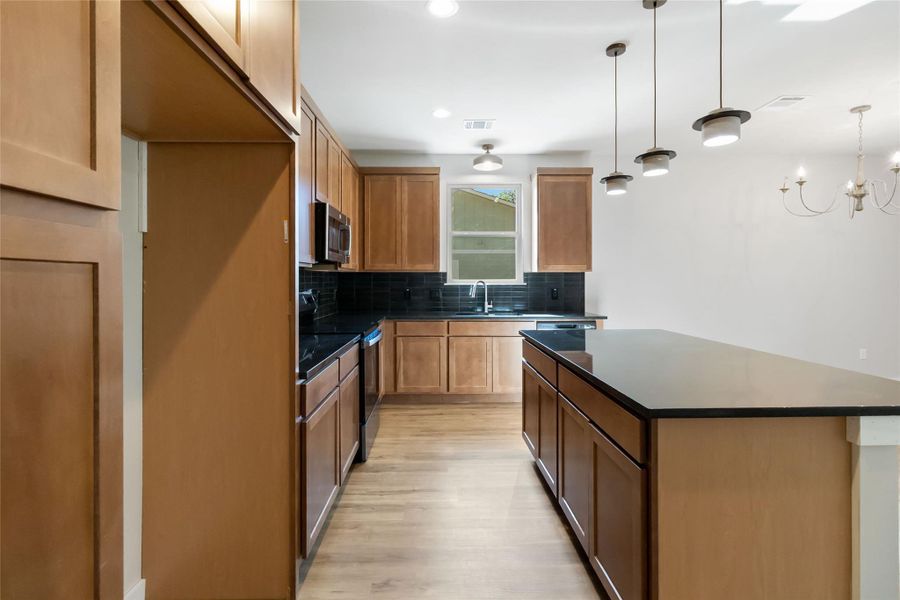 Kitchen featuring dark countertops, range with electric stovetop, backsplash, light wood finished floors, and recessed lighting Kitchen featuring dark countertops, range with electric stovetop, backsplash, light wood finished floors, and recessed lighting