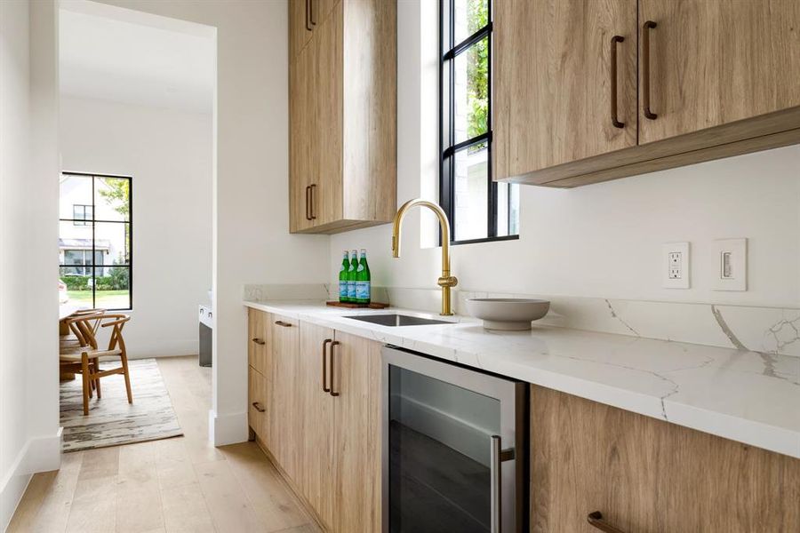 Kitchen with light stone counters, wine cooler, healthy amount of natural light, and modern cabinets Kitchen with light stone counters, wine cooler, healthy amount of natural light, and modern cabinets