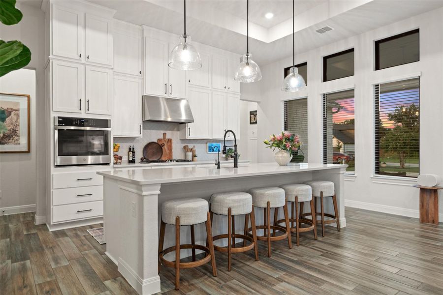 A contemporary kitchen features a spacious island with seating, integrated appliances, and tall windows illuminating the space. A contemporary kitchen features a spacious island with seating, integrated appliances, and tall windows illuminating the space.