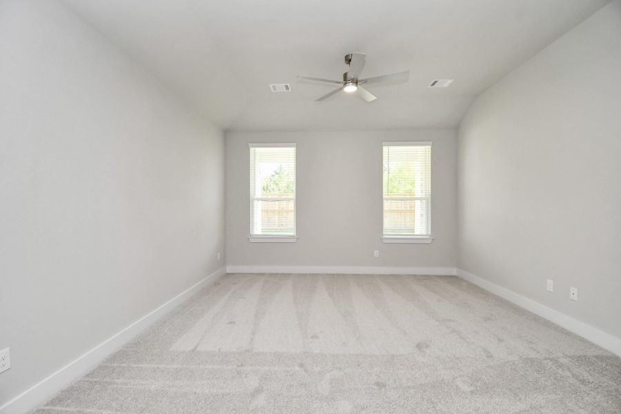 Escape to tranquility in this spacious primary room, adorned with plush carpeting and bathed in the soothing hues of warm paint colors, creating a cozy retreat for relaxation. Sample photo of completed home with similar floor plan. Actual colors and selections may vary.