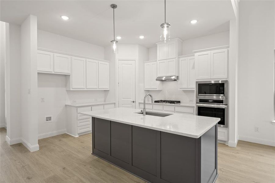 Kitchen with stainless steel appliances, a sink, white cabinetry, light wood-style flooring, and recessed lighting