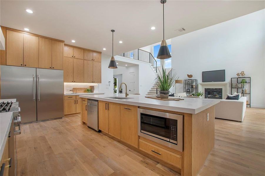 Kitchen featuring built in appliances, a sink, light brown cabinets, light wood-type flooring, and recessed lighting Kitchen featuring built in appliances, a sink, light brown cabinets, light wood-type flooring, and recessed lighting