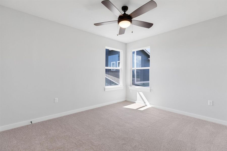 Carpeted empty room featuring baseboards and ceiling fan