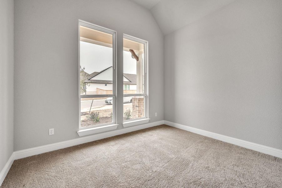 Carpeted spare room with lofted ceiling and baseboards Carpeted spare room with lofted ceiling and baseboards
