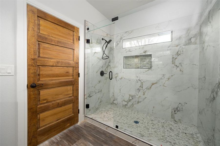 Bathroom featuring a marble finish shower and dark wood-style floors