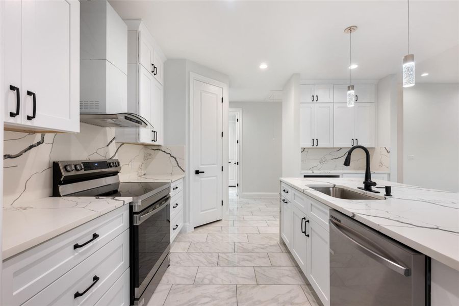 Kitchen featuring stainless steel appliances, hanging light fixtures, white cabinetry, light stone countertops, and light marble finish floors