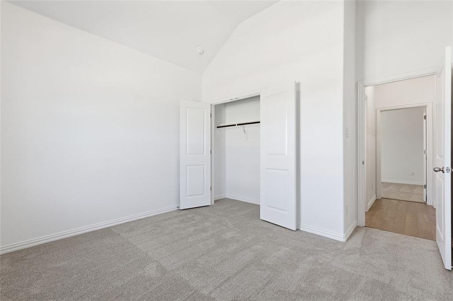 Spacious interior room featuring light gray carpeting, white baseboards, and a white interior door with a paneled design