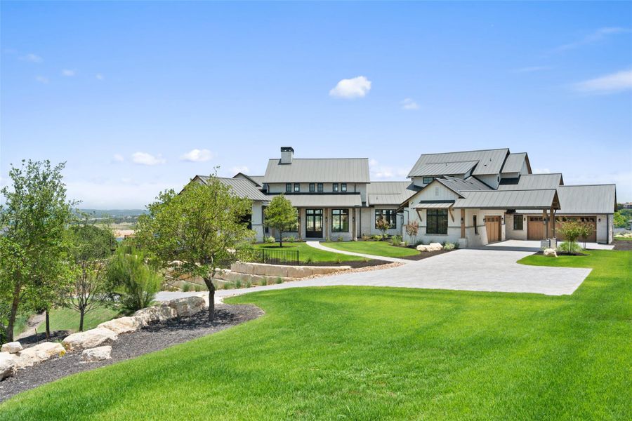 Rear view of property with a lawn, decorative driveway, a metal roof, and a standing seam roof