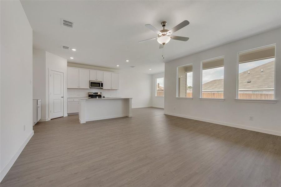 Unfurnished living room featuring a healthy amount of sunlight, ceiling fan, and hardwood / wood-style floors