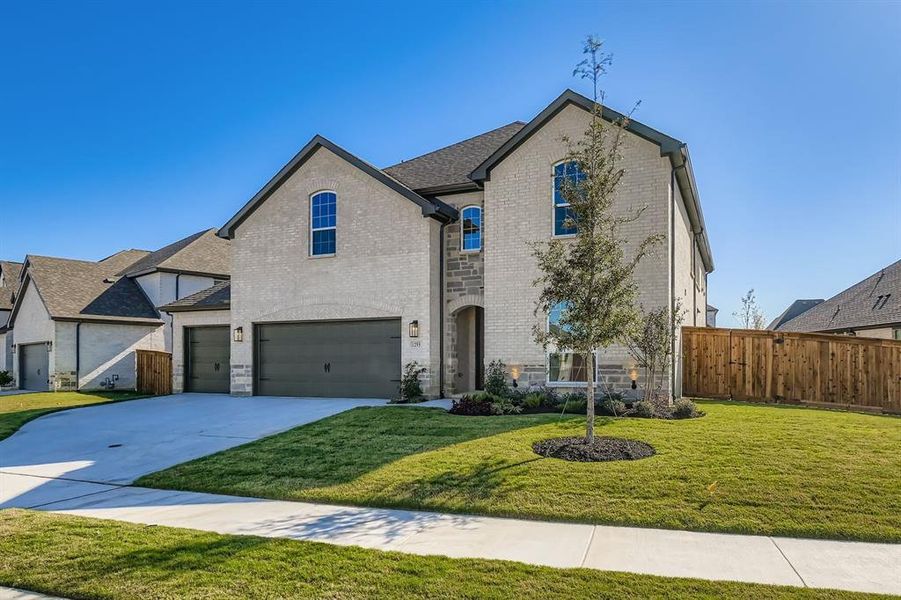 French country inspired facade featuring brick siding, an attached garage, and concrete driveway