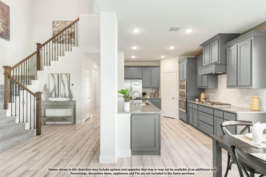 Open kitchen with gray cabinets, granite countertops, and staircase visible in adjacent entryway