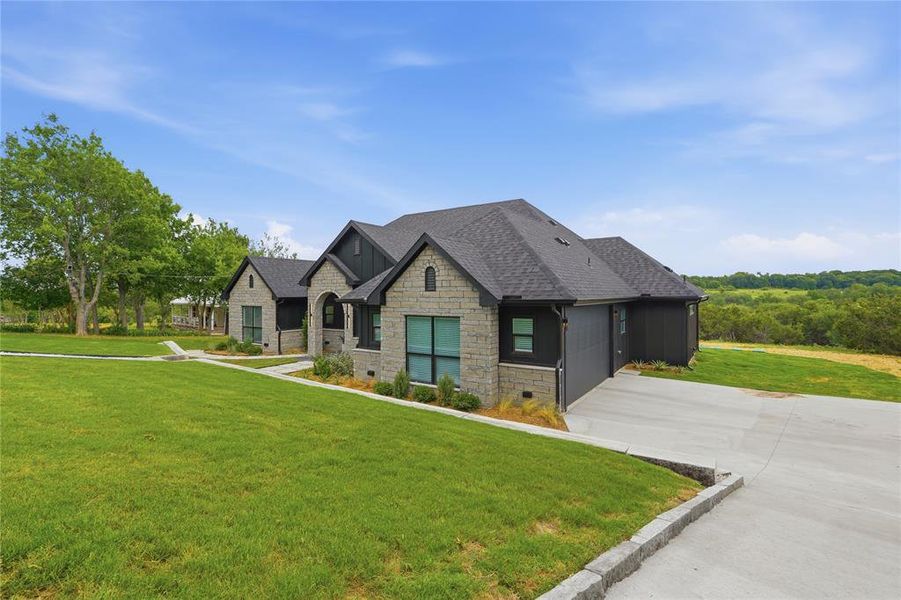 Stone facade residence with a dark shingle roof and a concrete driveway
