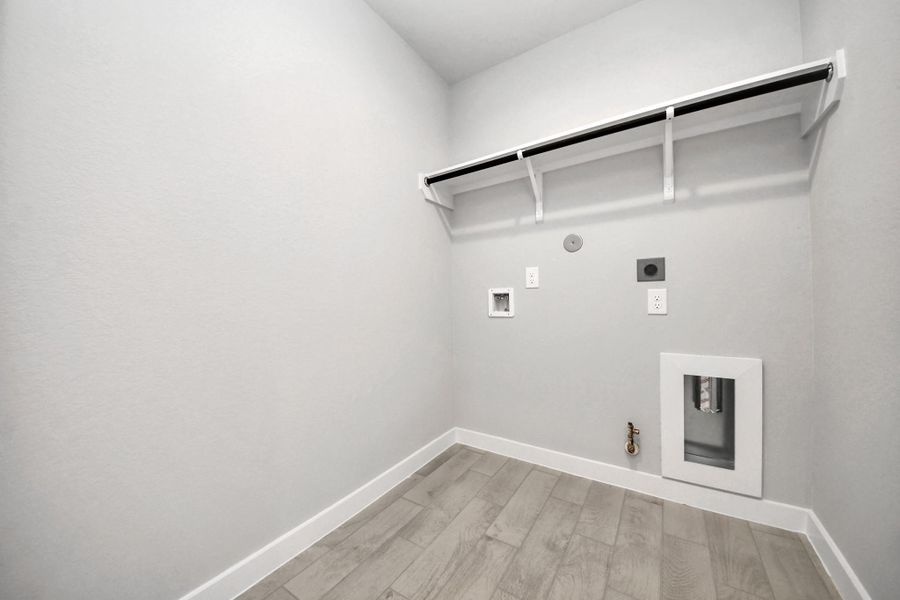 A perfect blend of functionality and comfort. Capture the essence of easy living with a first-floor laundry room, thoughtfully equipped with shelving for effortless organization. Both electric and gas connections available. Sample photo of completed home with similar floor plan. Actual colors and selections may vary.