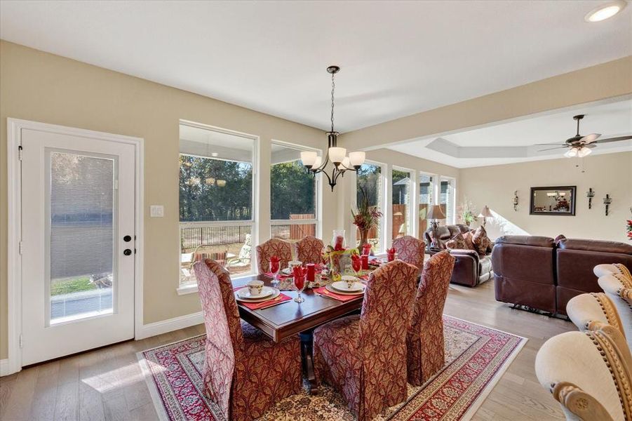 Dining space with hardwood / wood-style flooring, a raised ceiling, a chandelier, and ceiling fan Dining space with hardwood / wood-style flooring, a raised ceiling, a chandelier, and ceiling fan