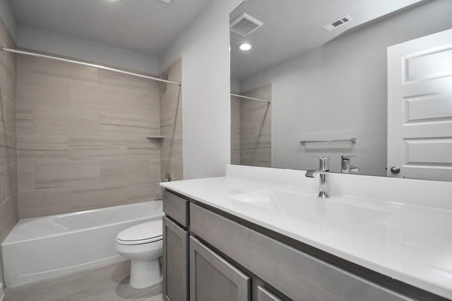 Secondary bath features tile flooring, bath/shower combo with tile surround, light stained wood cabinets, beautiful light countertop. Secondary bath features tile flooring, bath/shower combo with tile surround, light stained wood cabinets, beautiful light countertop.