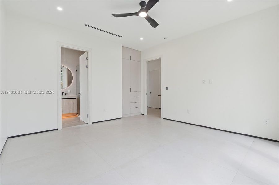 Neutral interior featuring large-format tile flooring, built-in floor-to-ceiling cabinetry, recessed lighting, and a modern three-blade ceiling fan
