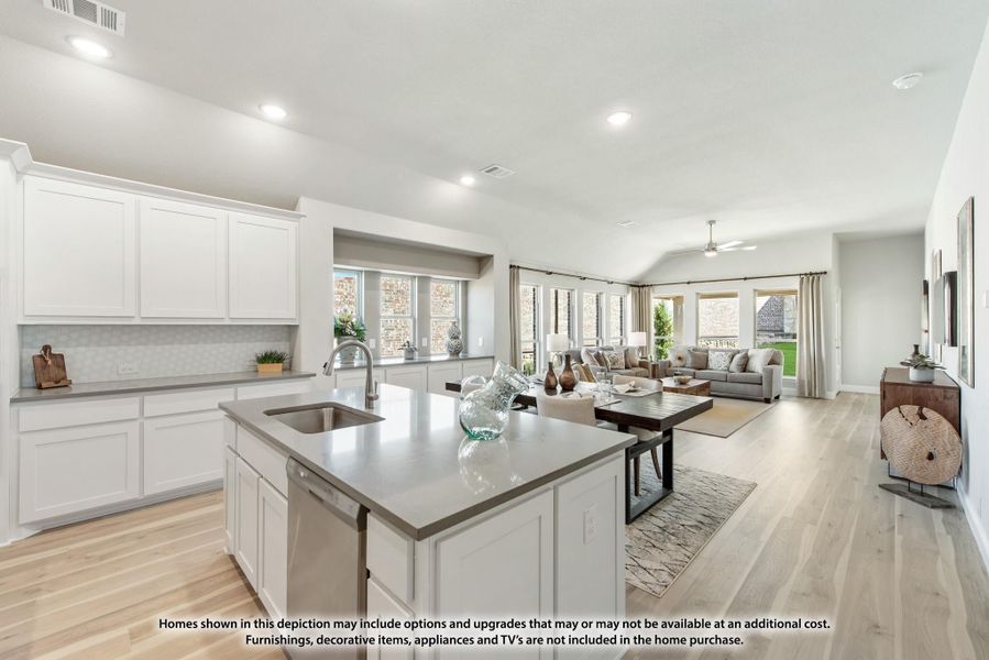 Open-concept kitchen with white cabinets and island flowing into living room with hardwood floors Open-concept kitchen with white cabinets and island flowing into living room with hardwood floors