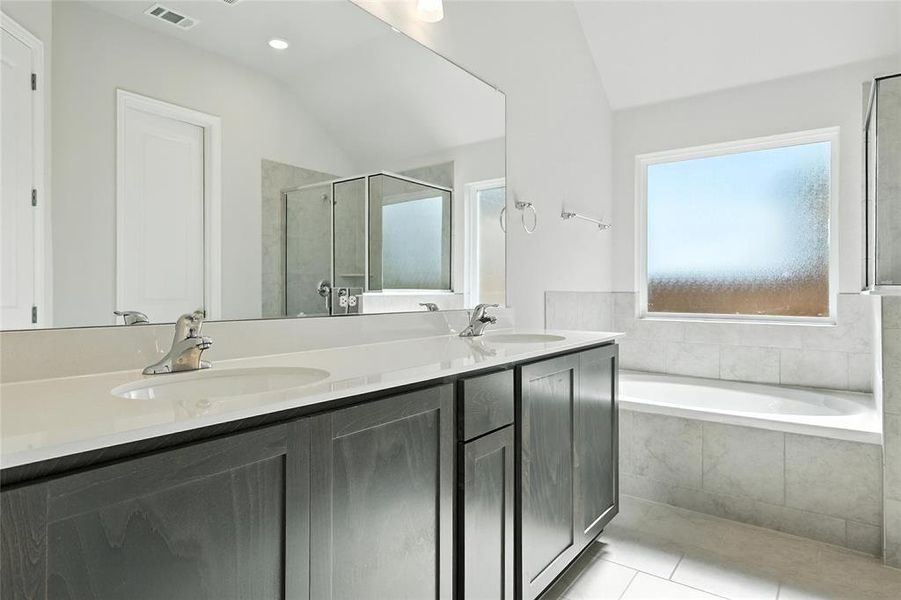 Bathroom featuring double vanity, a stall shower, a garden tub, light tile patterned floors, and lofted ceiling